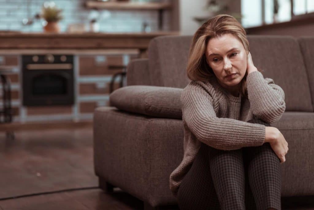 a woman sitting on the floor suffering from the effects of drug addiction