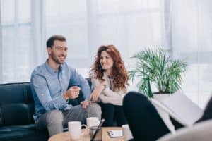 two people sit on a couch possibly enjoying the benefits of psychiatric treatment