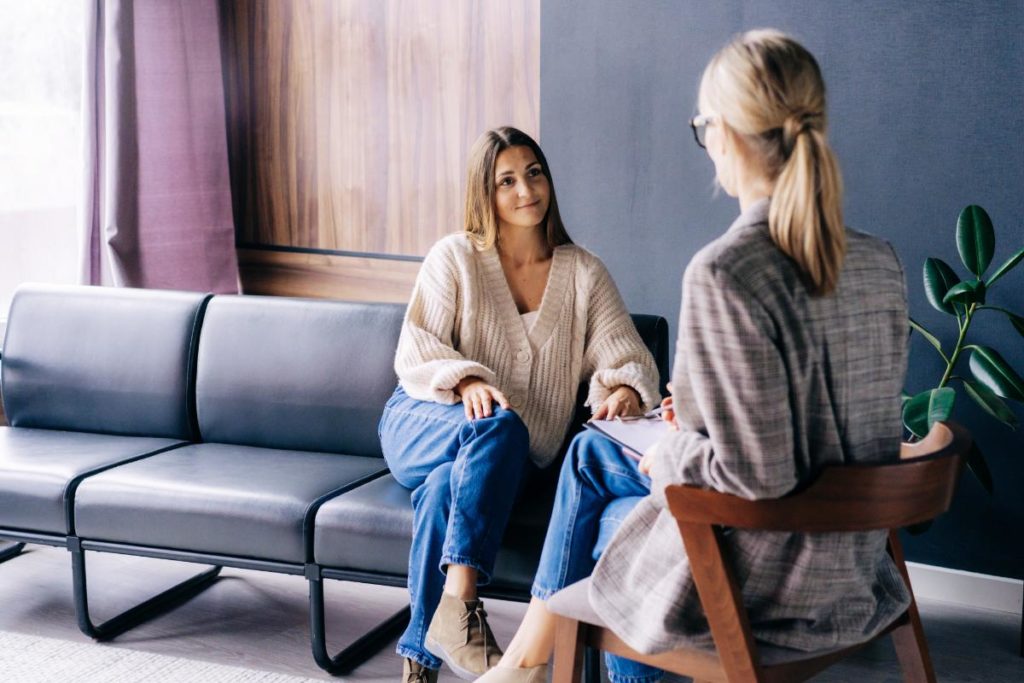 Woman on couch with therapist learning about the benefits of cognitive-behavioral therapy