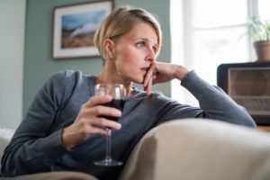 woman holding wine on couch considering anxiety and alcohol abuse