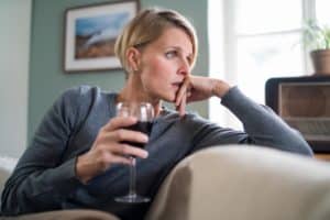 woman holding wine on couch considering anxiety and alcohol abuse