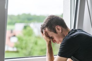 a person stands at a window leaning into their hands struggling with commonly abused prescription drugs