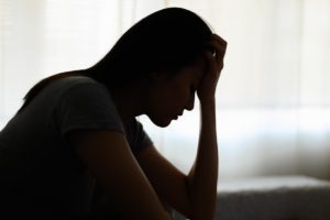 a person puts their head in their hands in a silhouette image dealing with the dangers of mixing alcohol and prescription drugs