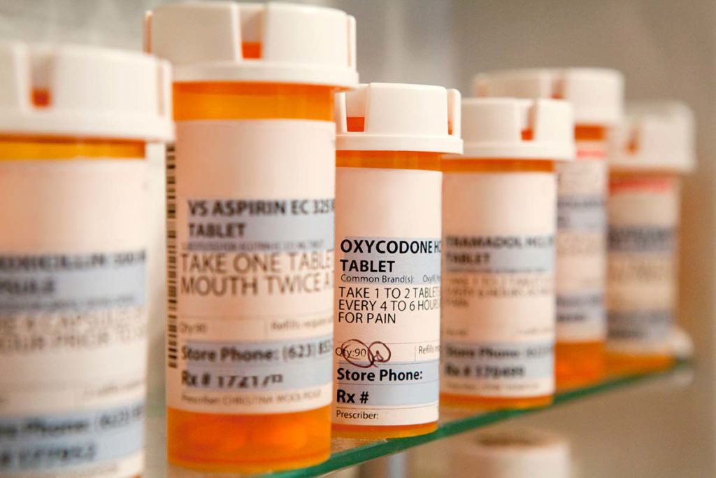 a list of prescription pill bottles in a medicine cabinet representing prescription drug abuse