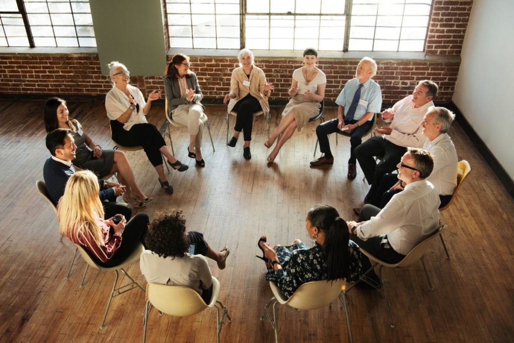 a group of people sit in a circle in a room while participating in an addiction support groups