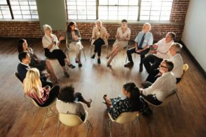 a group of people sit in a circle in a room while participating in an addiction support groups