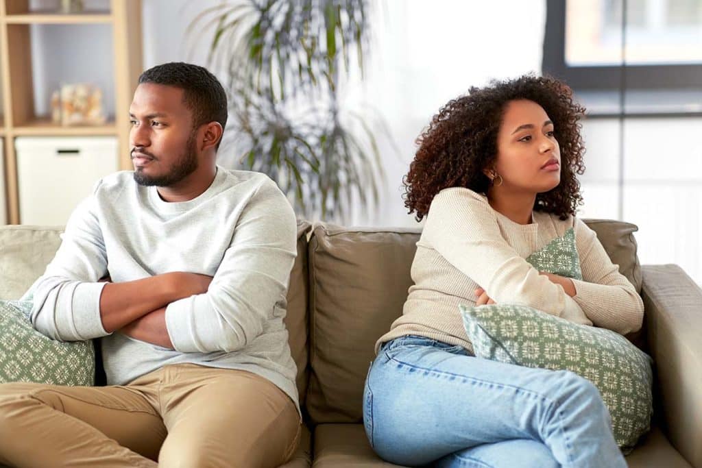 two people sitting on a couch mad at each other because of marijuana addiction