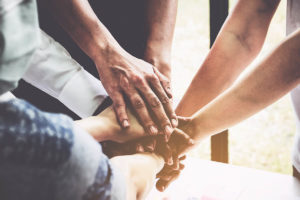 a group of people puts their hands together in a circle in a support groups