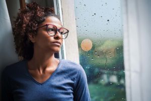 a person looks sadly out of a window while handling depression