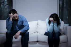 a couple looks strained as the sit on the couch as they realize that meth addiction affects relationships
