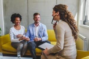 a therapist talks to a couple sitting on a yellow couch about activities for family therapy