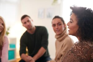 a person is talking in a group of people about the types of group therapy activities that can help well being
