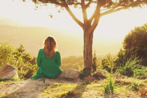 a person sits near a tree on a sunny day after leaning you can improve your mood by going outside