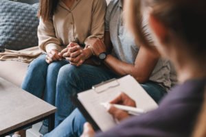 Man squeezes loved ones arm as they talk to therapist and discover the many benefits of family therapy