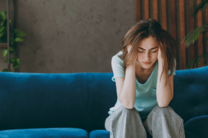 Woman sits on couch as she discovers signs of struggling with PTSD