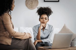 Woman sits on couch and wonders about cocaine rehab while talking to therapist