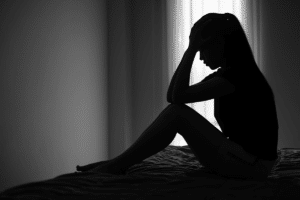 Woman sits on bed in agony, struggling with symptoms of polysubstance abuse