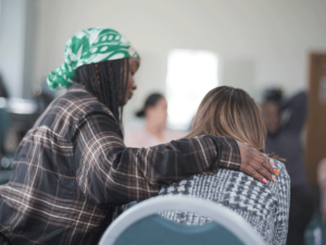 Woman puts arm around peer as they discover how an alumni program can help with relapse prevention